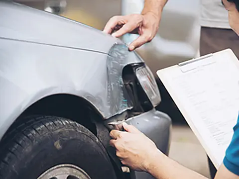 Perito revisando los daños de un auto chocado para un reclamo por accidente de tránsito
